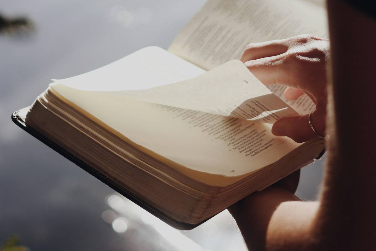 Eine Hand blättert in einer Bibel.
