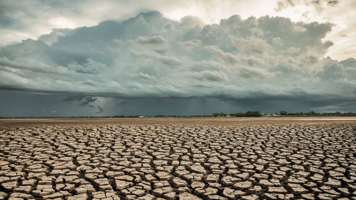 Eine Regenwolke zieht über ein ausgetrocknetes Stück Land.