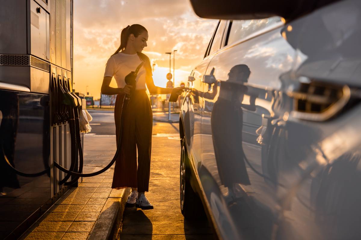 Eine Frau tankt im Sonnenuntergang ihr Auto an der Tankstelle