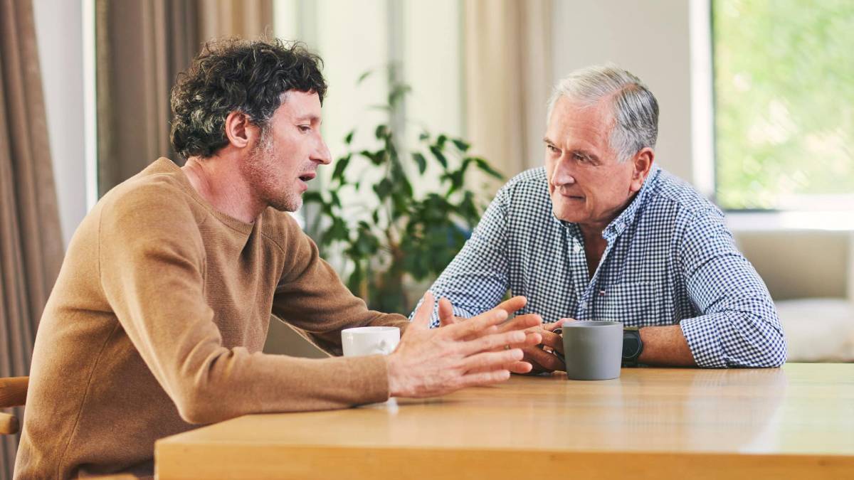 Ein junger und ein älterer Mann unterhalten sich an einem Tisch