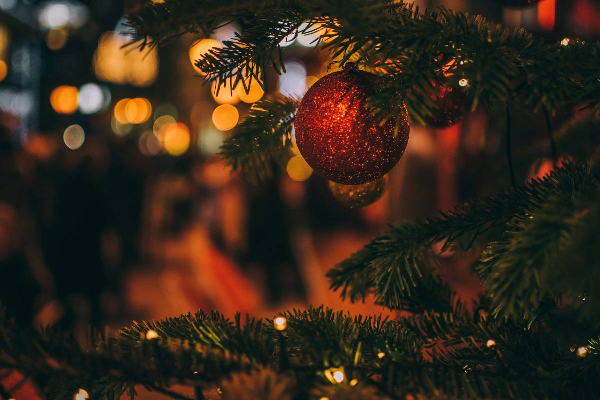Eine rote, glitzernde Kugel hängt an einem Weihnachtsbaum.