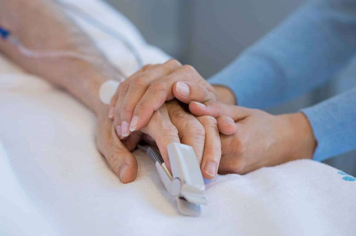 Frau hält die Hand eines Patienten