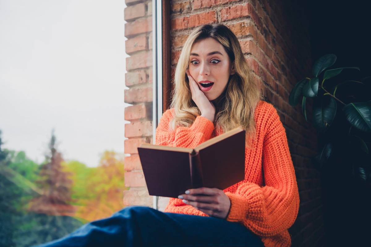 Frau liest Buch und schaut überrascht